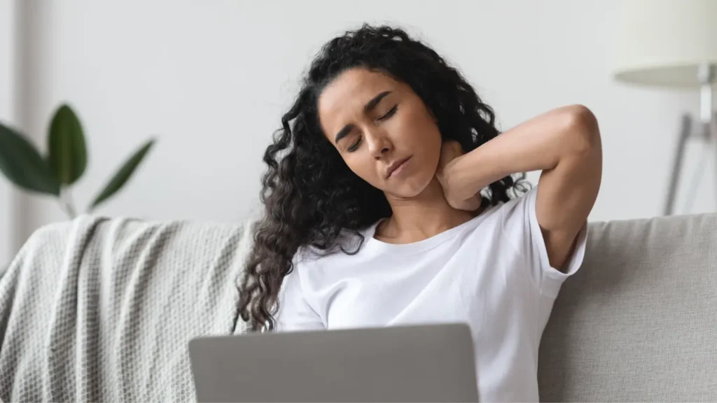 Bolečina v vratu pri delu z računalnikom – ženska drži vrat zaradi napetosti