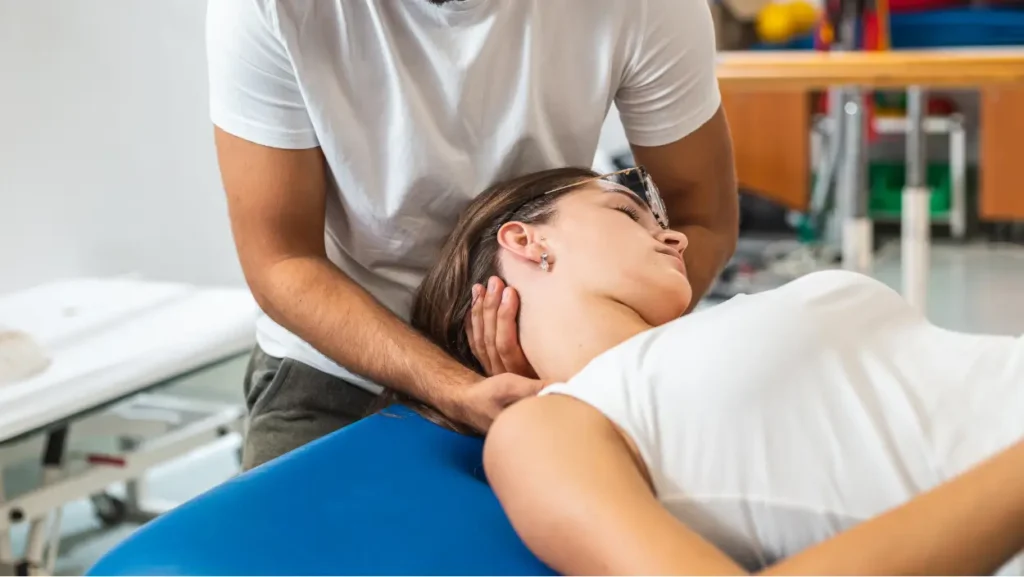 Fizioterapevt izvaja manualno terapijo vratu pri pacientki z bolečinami v vratu