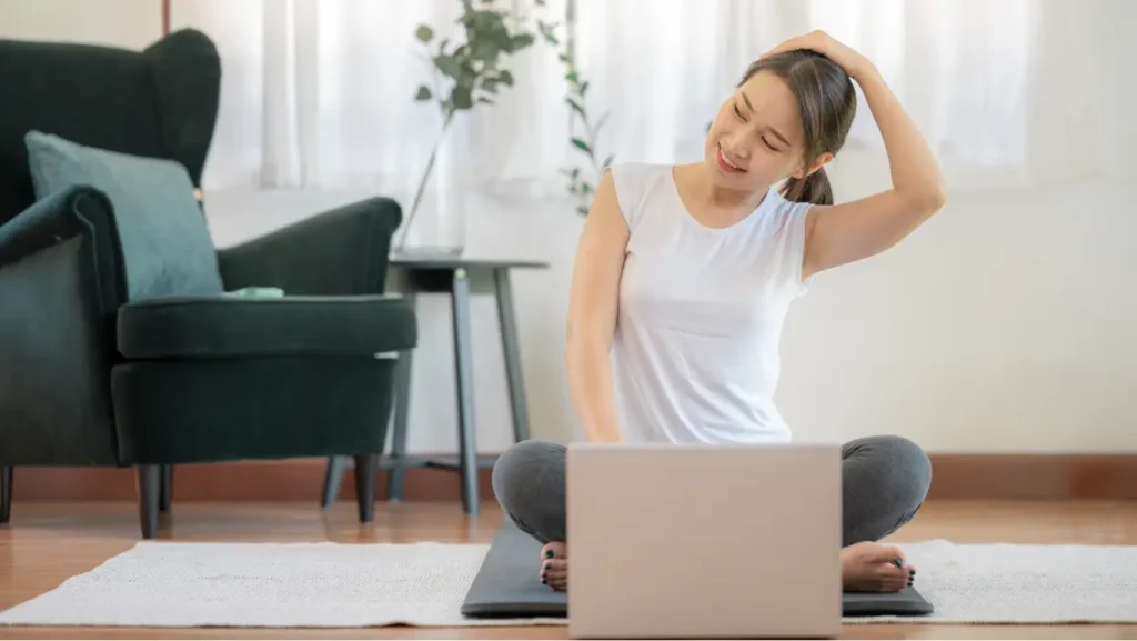 Raztezne vaje za bolečine v vratu – ženska izvaja vajo doma pred računalnikom