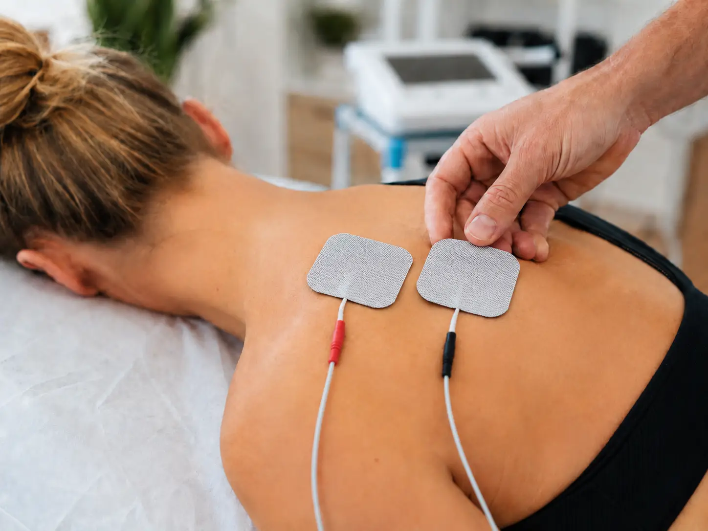 Elektroterapija z dvema elektrodama na hrbtu pacientke